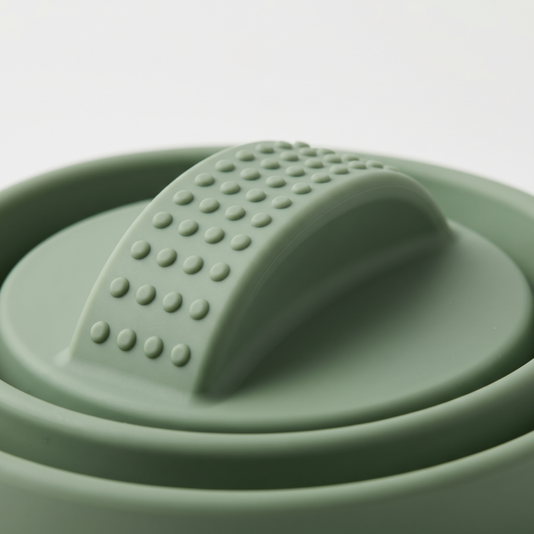 Safe-grip handle lifting the sage green Circular microwave cover from a bowl